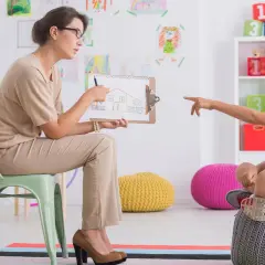 Pedagog szkolny z dzieckiem omawia rysunek domu. Czy po resocjalizacji można być pedagogiem szkolnym?
