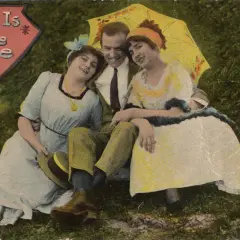 Uśmiechnięty mężczyzna w otoczeniu dwóch kobiet pod parasolem. To jest życie, jak głosi napis.