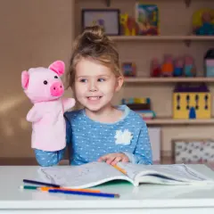 Dziewczynka z pluszową świnką uczy się, co to monosylaby, rysując w zeszycie.