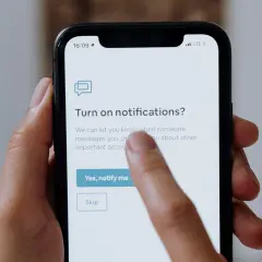 Palec dotyka ekranu telefonu, wybierając opcję "Yes, notify me" (Tak, powiadom mnie) na ekranie z pytaniem o włączenie powiadomień po polsku.