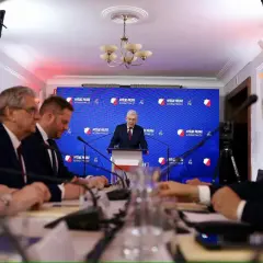 Ludzie siedzą przy stole, słuchając przemówienia. To pokazuje, co można robić po prawie – brać udział w debatach i konferencjach.