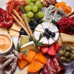 Wykwintna deska serów i wędlin, czyli polskie charcuterie: sery pleśniowe, camembert, owoce, oliwki, krakersy i dip.