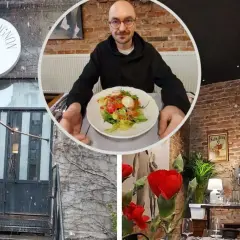 Voila, co znaczy to bistro! Mężczyzna z okularami prezentuje sałatkę w przytulnym wnętrzu z ceglanymi ścianami i stylowymi lampami.