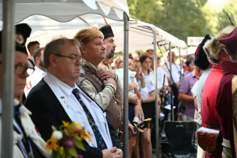 Uroczystość z udziałem mężczyzn w historycznych strojach, jeden z nich ma szablę. Czy to jakaś **maledizione po polsku**?