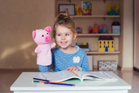 Dziewczynka z pluszową świnką uczy się, co to monosylaby, rysując w zeszycie.