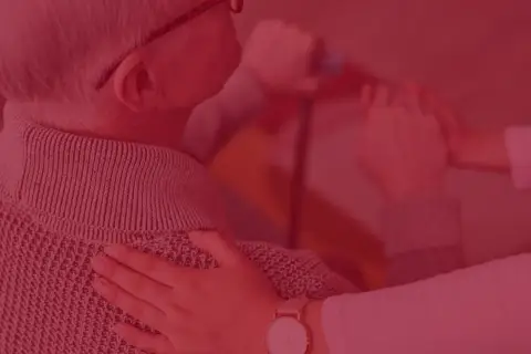 Pracownik socjalny wspiera seniora w domu opieki lub podczas wizyty domowej, oferując pomoc i troskę.