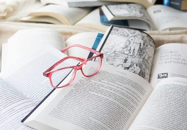 Różowe okulary leżą na otwartych książkach. Idealne do czytania po francusku, gdy tekst jest trudny.