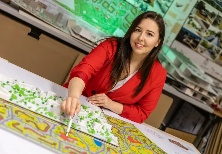 Kobieta w czerwonej marynarce pracuje nad modelem urbanistycznym, pokazując, co można robić po gospodarce przestrzennej: projektować i tworzyć przyszłość miast.