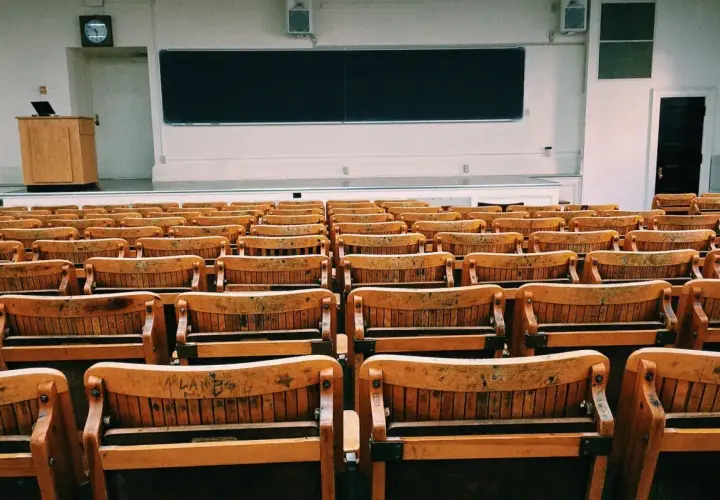 Puste drewniane ławki w sali wykładowej, jakby czekające na studentów w futurystycznym francuskim uniwersytecie.