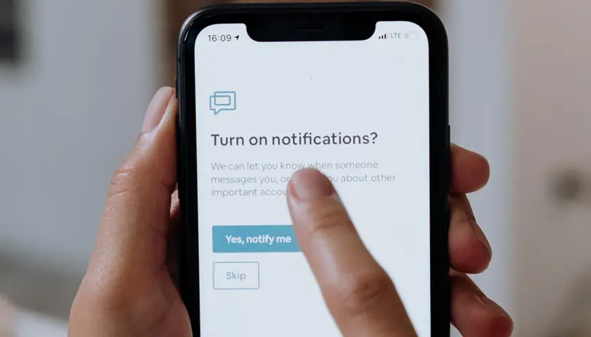 Palec dotyka ekranu telefonu, wybierając opcję "Yes, notify me" (Tak, powiadom mnie) na ekranie z pytaniem o włączenie powiadomień po polsku.