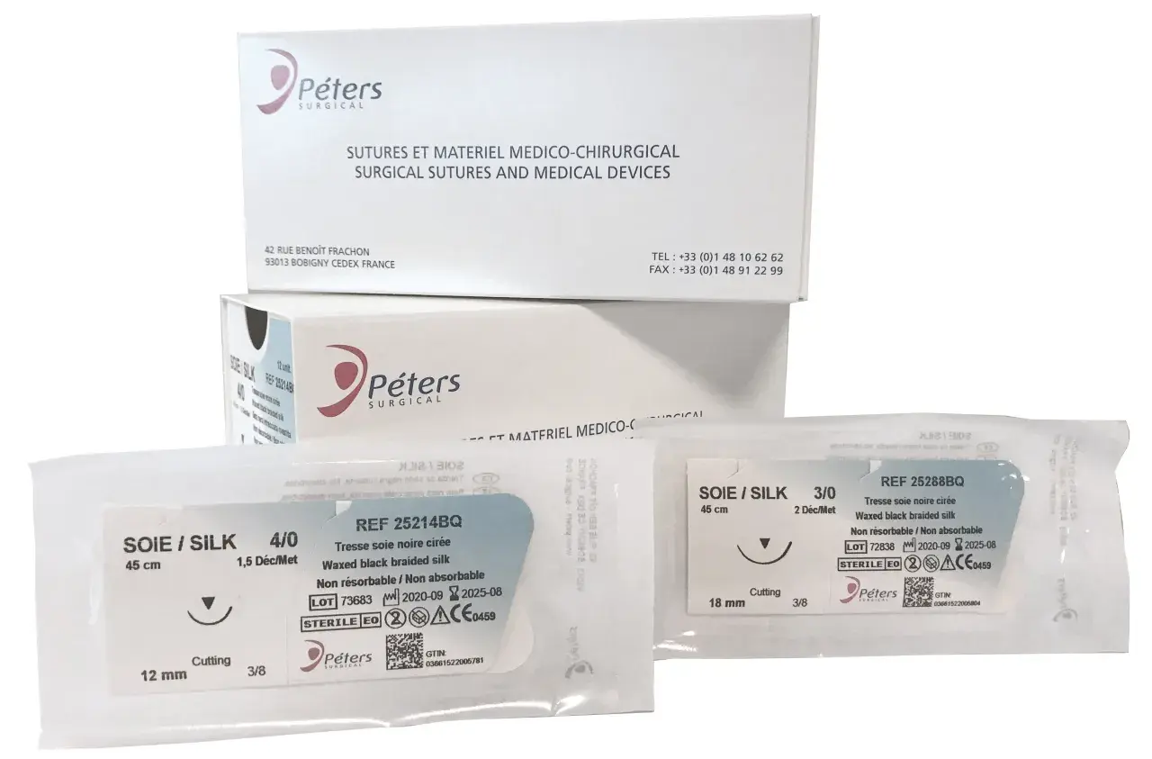 Opakowania z szwami chirurgicznymi Peters Surgical. Widać dwa pakiety z szwami jedwabnymi, w tym jeden z igłą tnącą.