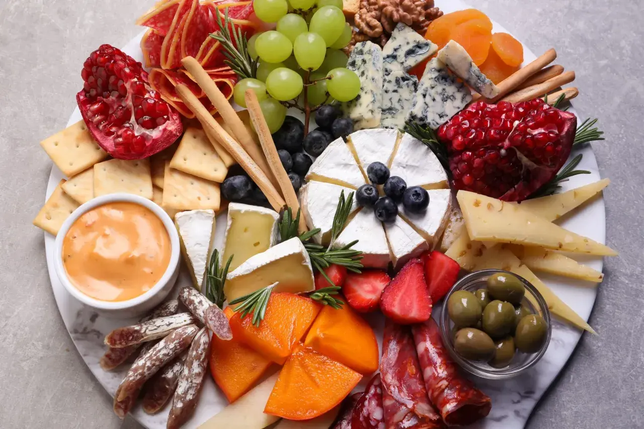Wykwintna deska serów i wędlin, czyli polskie charcuterie: sery pleśniowe, camembert, owoce, oliwki, krakersy i dip.