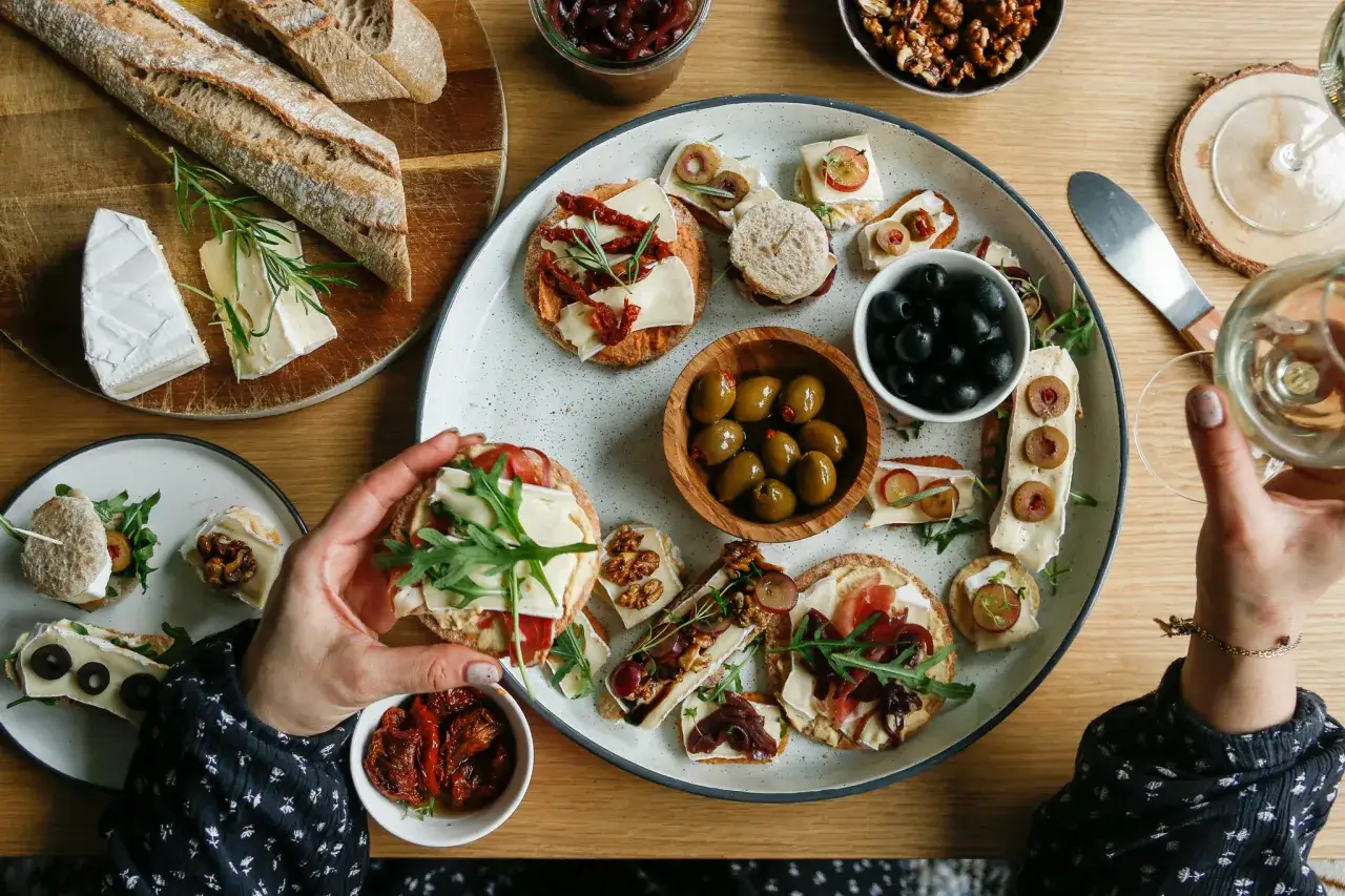 Pyszna deska serów i przekąsek, czyli charcuterie po polsku: bagietka, sery, oliwki, suszone pomidory i orzechy.