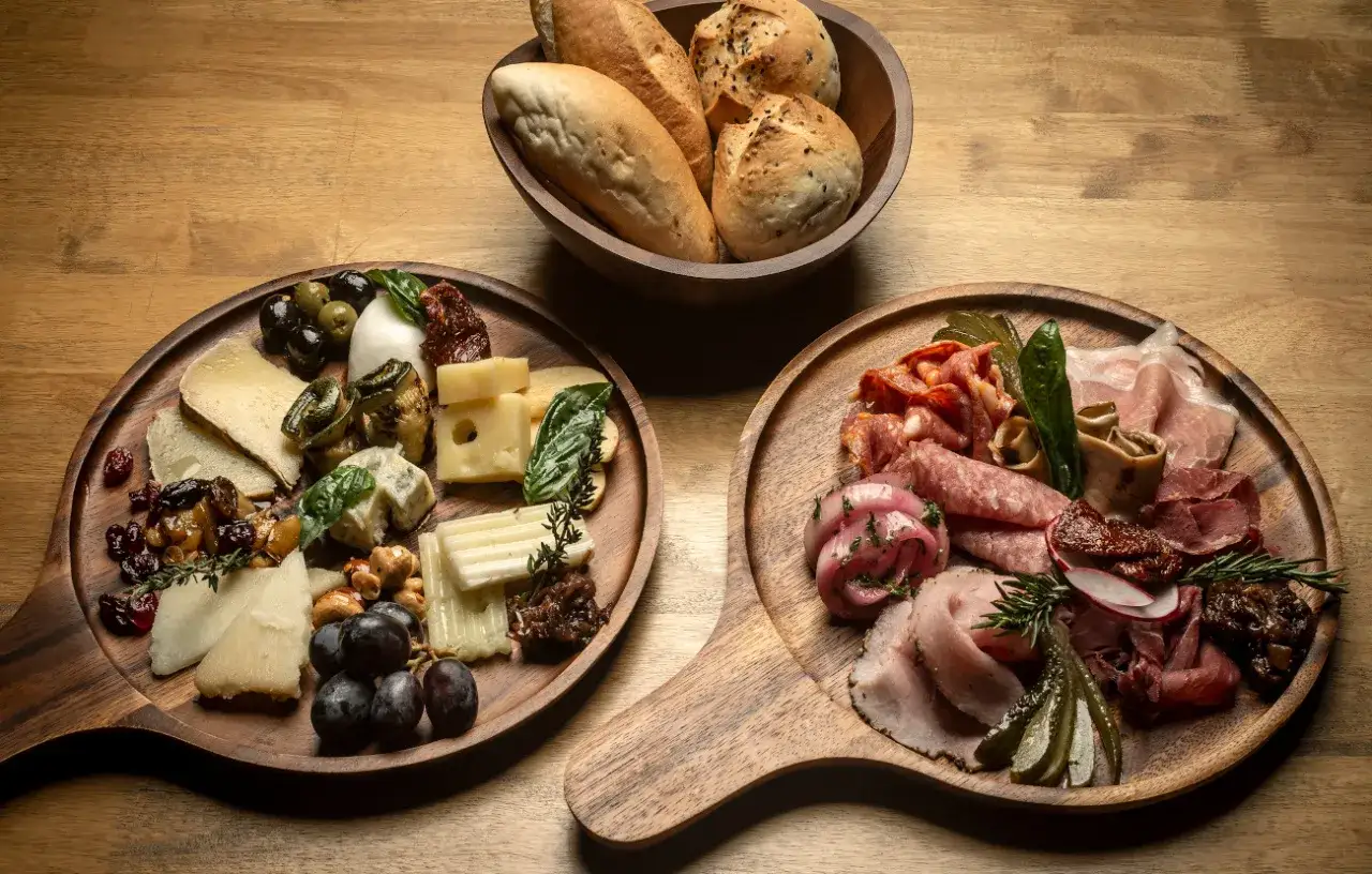 Dwie deski serów i wędlin, pieczywo w misce. Prawdziwa uczta, czyli charcuterie po polsku.
