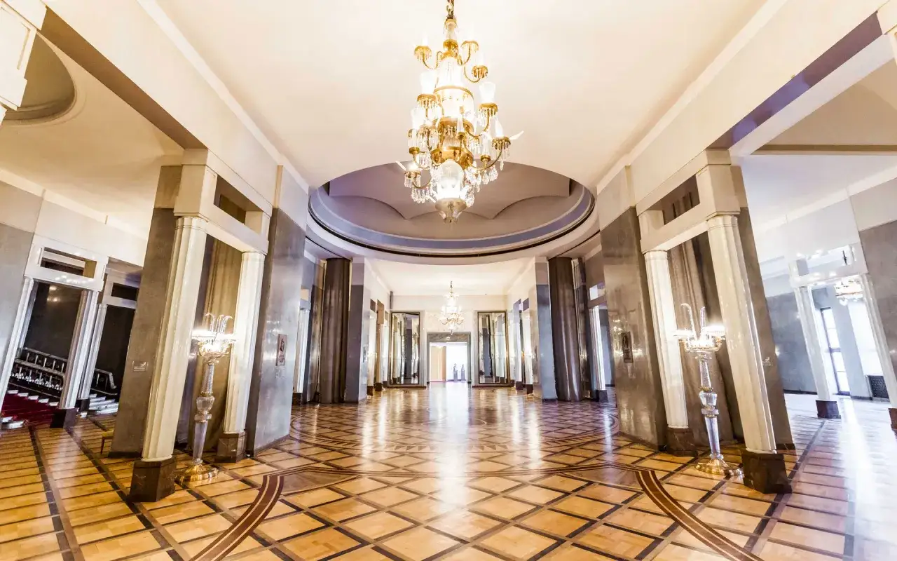 Elegancki foyer z kryształowymi żyrandolami i parkietem.