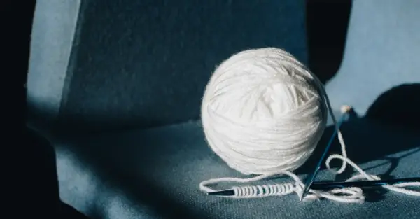 Biała, miękka wełna na drutach, gotowa do stworzenia czegoś ciepłego. Laine wool po polsku to po prostu wełna.